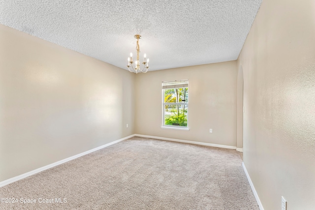 unfurnished room featuring carpet, a textured ceiling, and an inviting chandelier