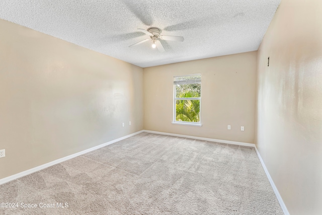 spare room featuring light carpet, a textured ceiling, and ceiling fan