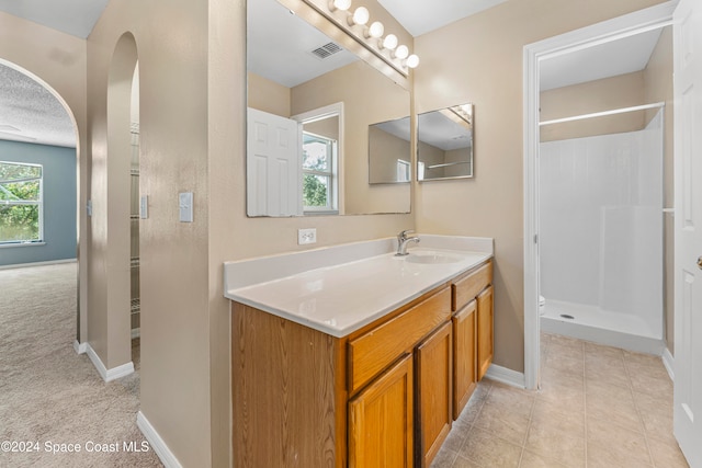 bathroom featuring vanity, a shower, and tile patterned flooring