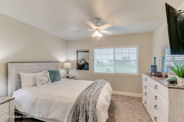 bedroom featuring light carpet, a textured ceiling, and ceiling fan