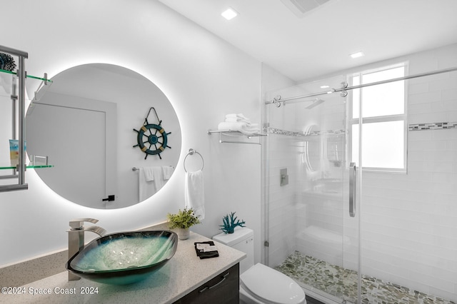 bathroom with a shower with door, vanity, and toilet