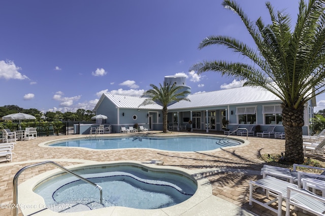 community pool featuring a patio area, a hot tub, and fence