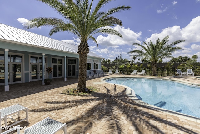 community pool featuring fence, a patio area, and french doors