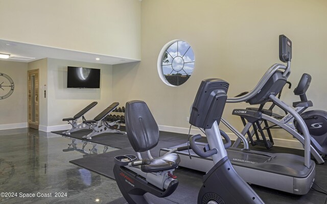 exercise room with a high ceiling and baseboards