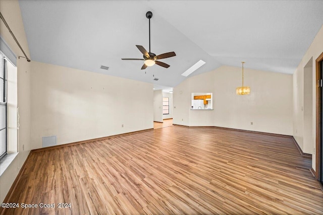 unfurnished living room featuring ceiling fan with notable chandelier, light hardwood / wood-style floors, high vaulted ceiling, and a skylight