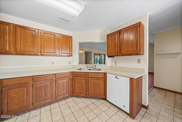 kitchen with a textured ceiling, light tile patterned flooring, sink, and dishwasher