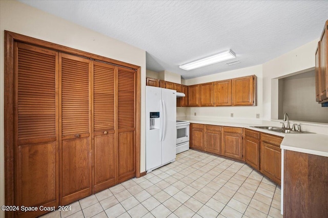 kitchen featuring a textured ceiling, sink, and white appliances