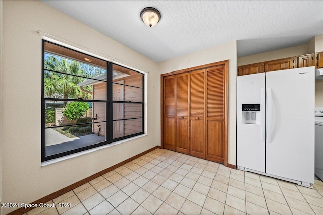 kitchen with white fridge with ice dispenser, a textured ceiling, and light tile patterned flooring