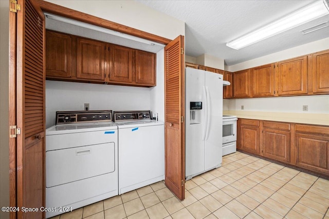 kitchen with independent washer and dryer, white appliances, light tile patterned floors, and a textured ceiling