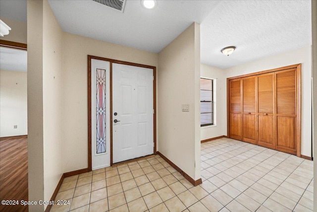 tiled foyer entrance with a textured ceiling