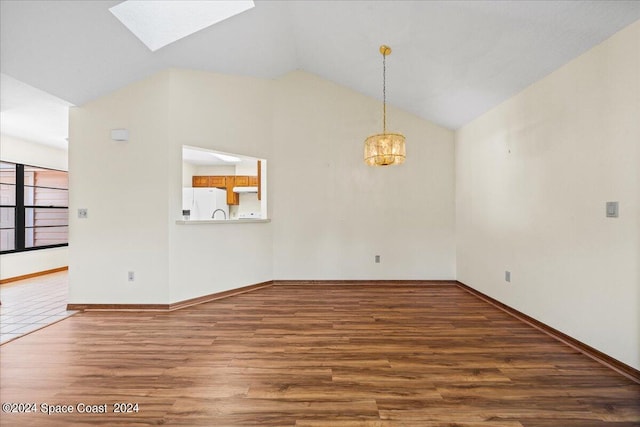 empty room with vaulted ceiling with skylight, a chandelier, and hardwood / wood-style flooring