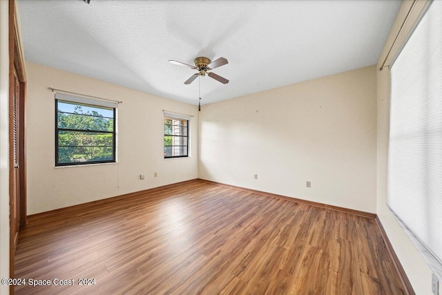 empty room with hardwood / wood-style flooring, a textured ceiling, and ceiling fan