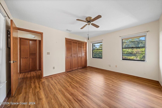 unfurnished bedroom with wood-type flooring, a closet, a textured ceiling, and ceiling fan