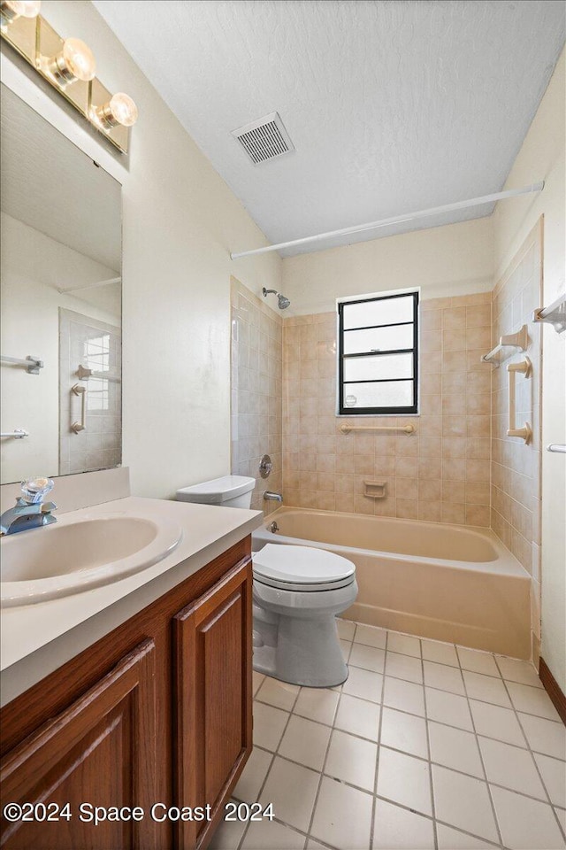 full bathroom with vanity, tiled shower / bath combo, tile patterned floors, toilet, and a textured ceiling