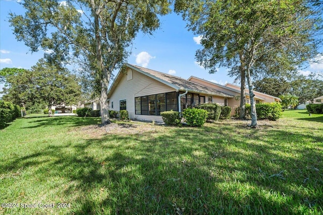 rear view of property with a sunroom and a lawn