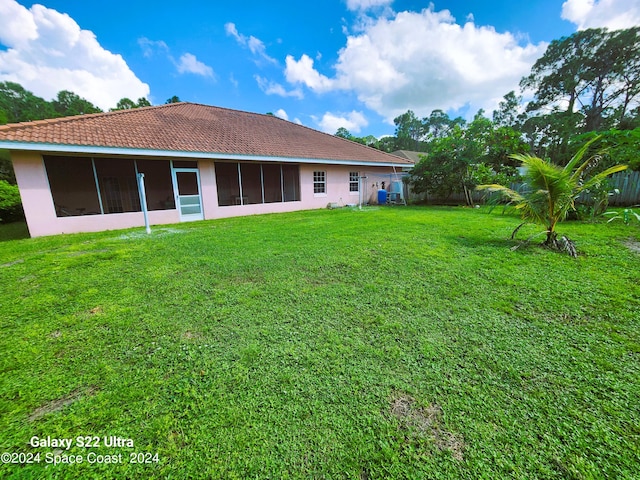 back of property featuring a sunroom and a lawn