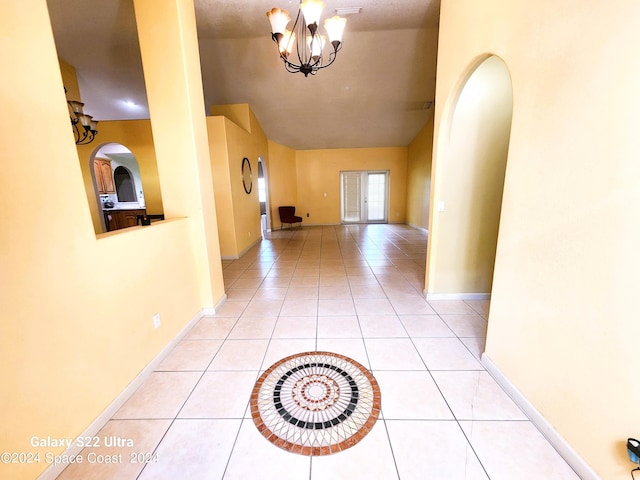 corridor featuring light tile patterned flooring and a notable chandelier