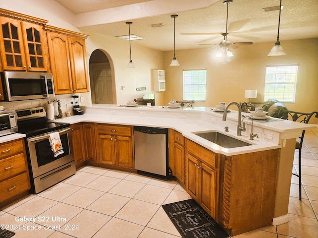 kitchen featuring a textured ceiling, sink, kitchen peninsula, a kitchen breakfast bar, and stainless steel appliances