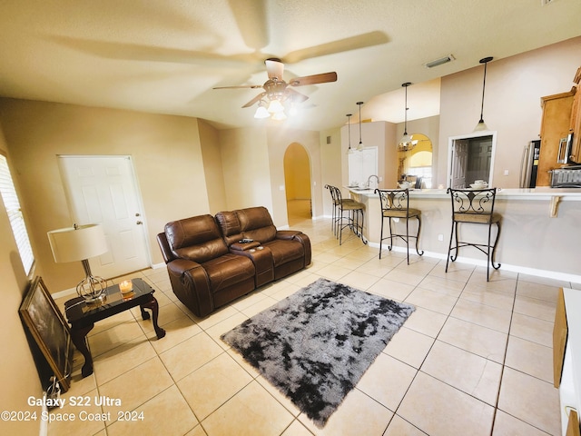 living room with ceiling fan, light tile patterned flooring, and lofted ceiling