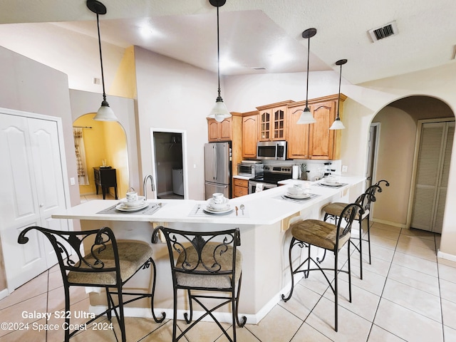 kitchen featuring kitchen peninsula, a breakfast bar area, light tile patterned floors, pendant lighting, and stainless steel appliances