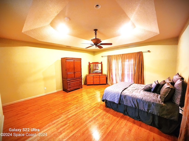 bedroom featuring a tray ceiling, ceiling fan, and hardwood / wood-style flooring