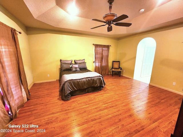 bedroom with ceiling fan, a textured ceiling, and light hardwood / wood-style floors