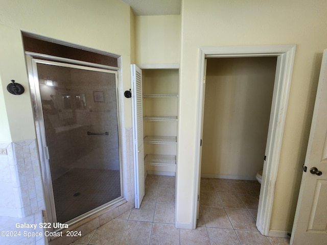 bathroom featuring tile patterned flooring, a shower with door, and toilet