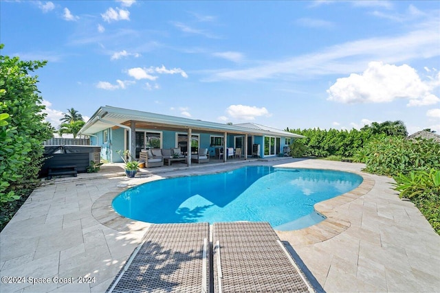 view of swimming pool with an outdoor living space, a hot tub, and a patio area