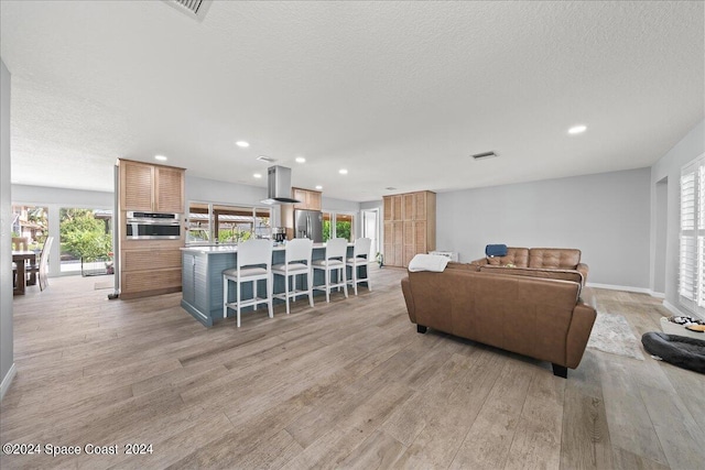 living room with a textured ceiling and light wood-type flooring