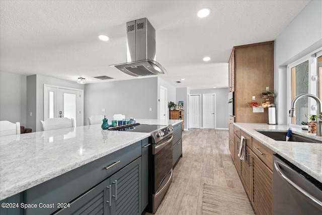 kitchen featuring a textured ceiling, sink, island exhaust hood, and appliances with stainless steel finishes