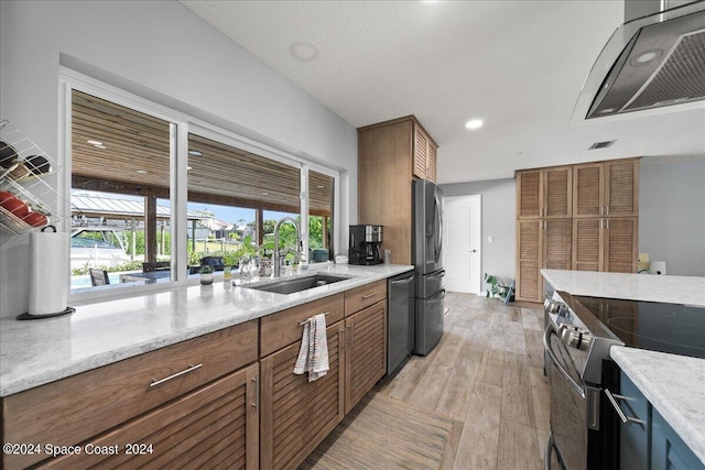 kitchen featuring light stone counters, sink, stainless steel appliances, and light hardwood / wood-style floors