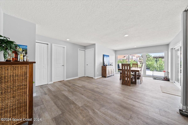 dining room featuring light wood-type flooring and a textured ceiling