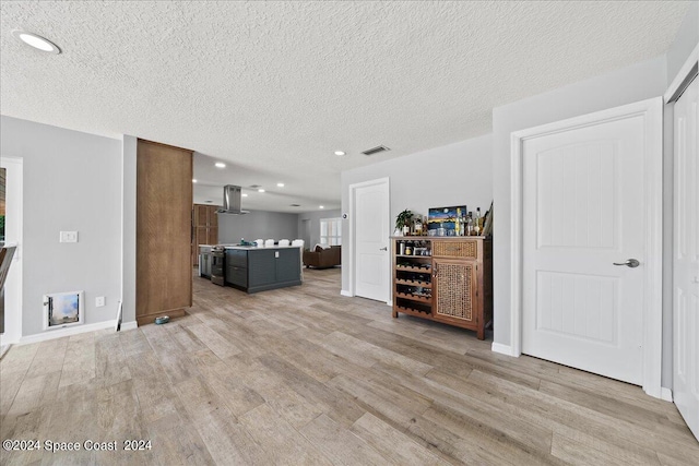 unfurnished living room with a textured ceiling and light hardwood / wood-style floors