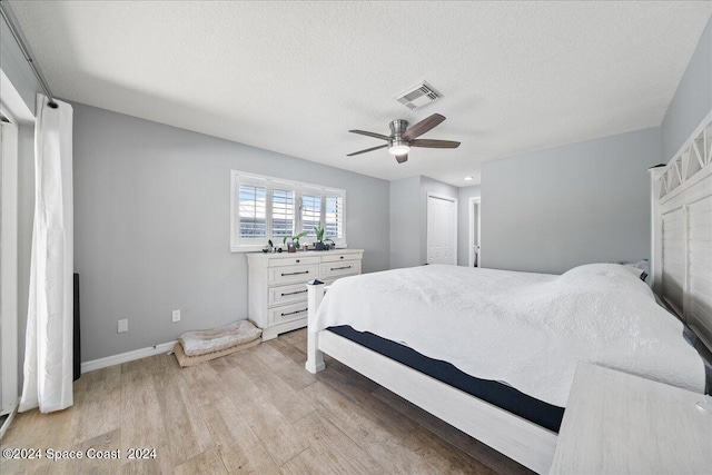 bedroom featuring ceiling fan, a closet, light hardwood / wood-style floors, and a textured ceiling