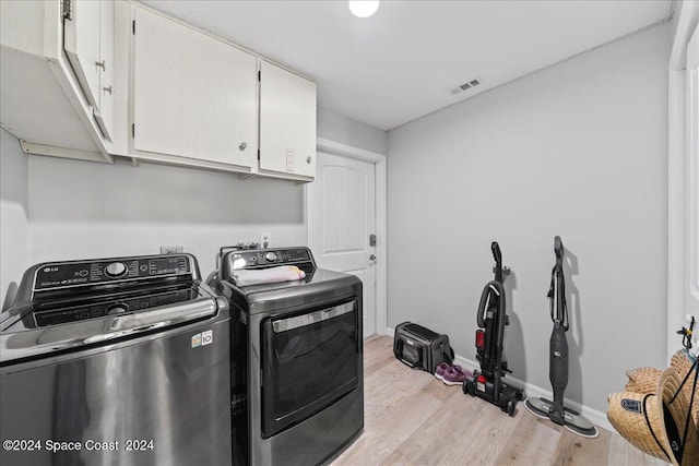 laundry area featuring washer and clothes dryer, cabinets, and light wood-type flooring