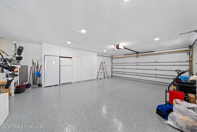 garage featuring white fridge and a garage door opener