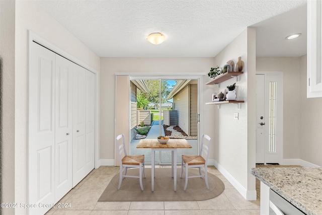 dining space featuring a textured ceiling and light tile patterned floors