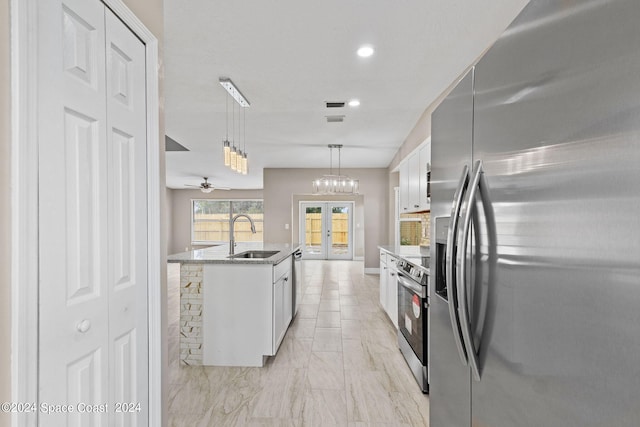 kitchen featuring pendant lighting, a kitchen island with sink, sink, white cabinetry, and stainless steel appliances