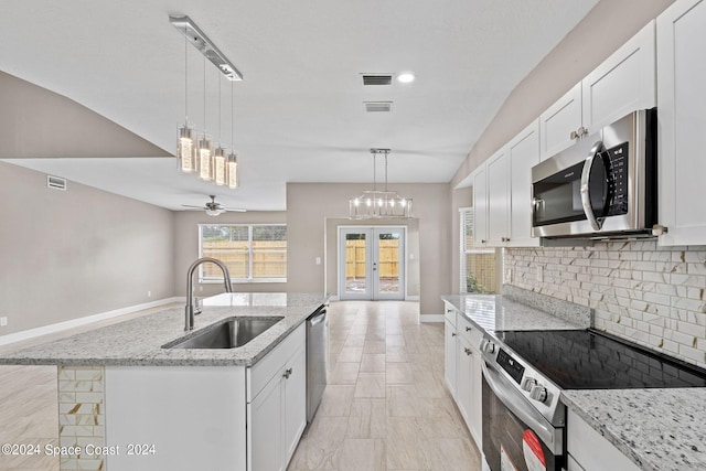 kitchen with appliances with stainless steel finishes, a kitchen island with sink, sink, and white cabinets