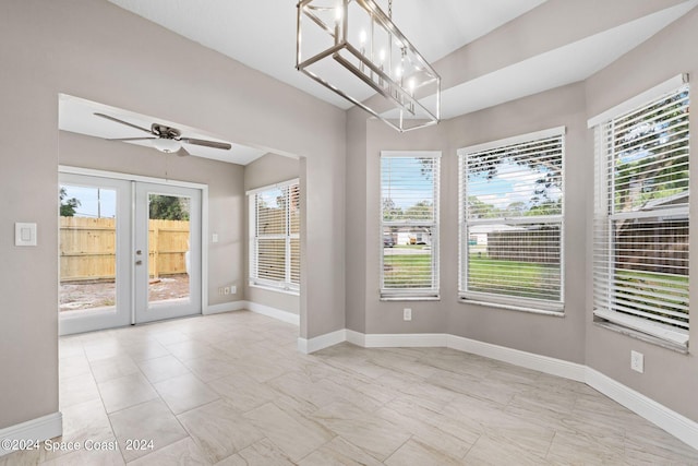 unfurnished room featuring ceiling fan with notable chandelier and french doors