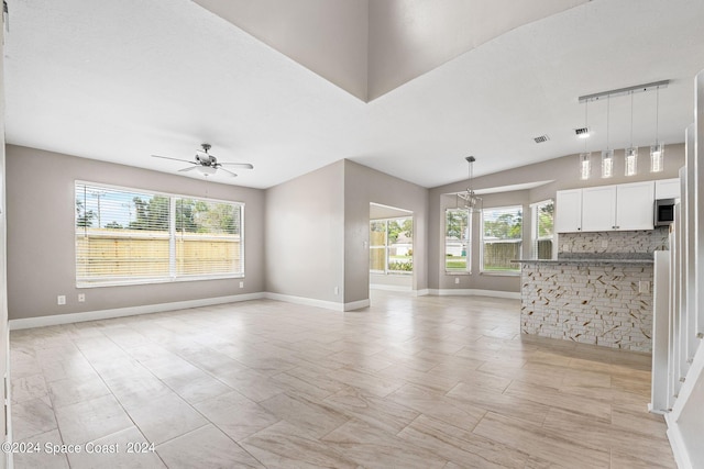 unfurnished living room with vaulted ceiling, ceiling fan, a healthy amount of sunlight, and rail lighting