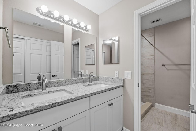 bathroom with a tile shower and vanity