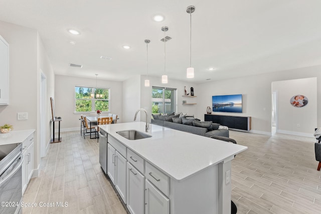 kitchen with an island with sink, decorative light fixtures, sink, and appliances with stainless steel finishes