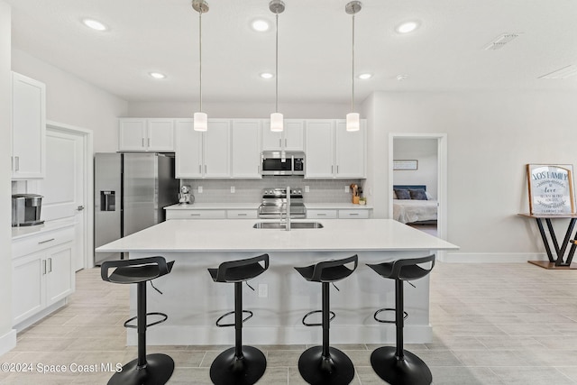 kitchen featuring pendant lighting, appliances with stainless steel finishes, sink, and white cabinetry