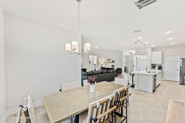 dining space featuring a notable chandelier, light hardwood / wood-style floors, and sink