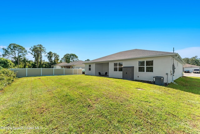 rear view of property featuring cooling unit and a lawn