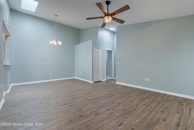 empty room with a towering ceiling, ceiling fan with notable chandelier, and wood-type flooring