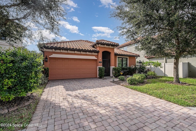694 Mission Bay Dr, Satellite Beach, FL 32937 - mediterranean / spanish-style home with an attached garage, decorative driveway, a tiled roof, and stucco siding