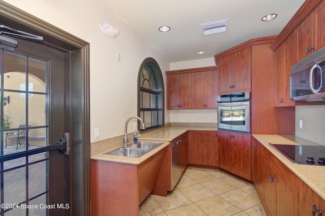 kitchen featuring appliances with stainless steel finishes, a textured ceiling, light tile patterned floors, and sink