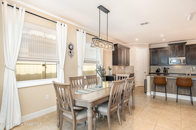 dining area with crown molding, plenty of natural light, and light tile patterned floors